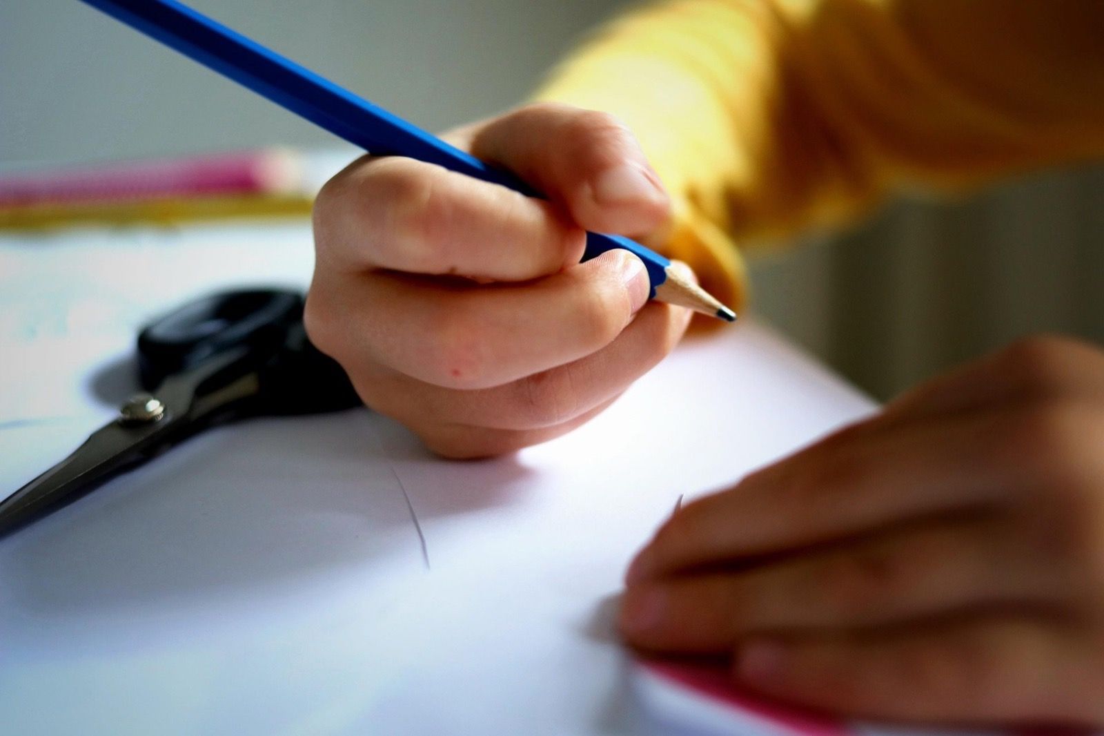 A child forming letters with a pencil during a writing task