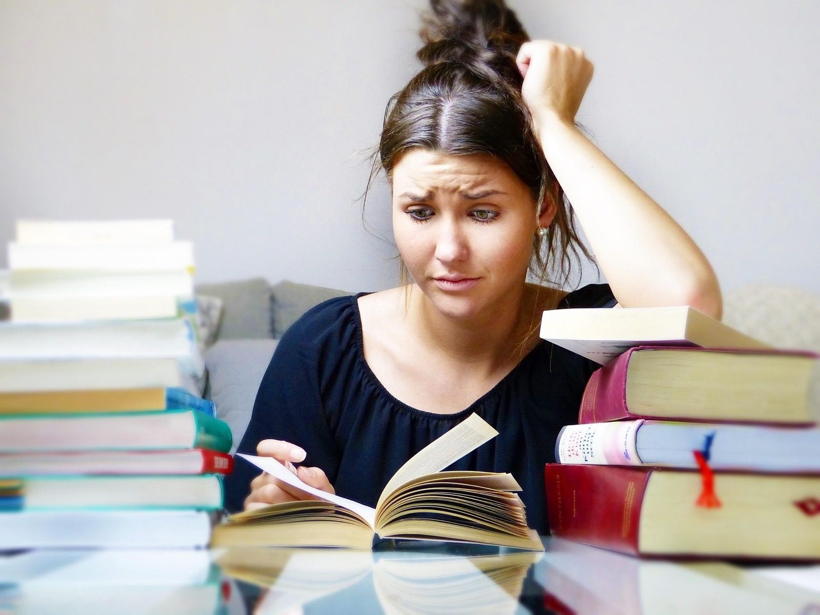 A teen resting their head on one hand, looking overwhelmed while studying at a desk